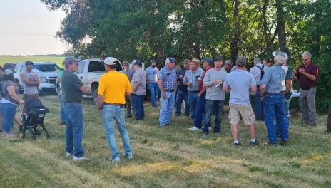 A group of farmers visit over supper after a plot tour.