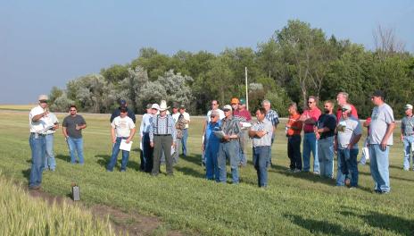 Greg Endres gestures at a field while speaking to several farmers.