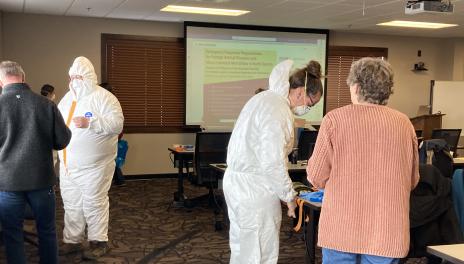 Trainees are practicing the proper use of personal protection equipment such as Tyvek suits.