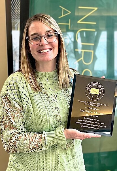 Photo of nursing faculty member Jill Johnson holding an award plaque designating her as North Dakota Nurse Educator of the Year