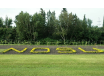 NDSU spelled out in flowers with green grass and trees in the background. 