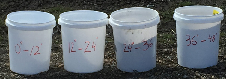 Four buckets of soil samples marked with depth they were taken