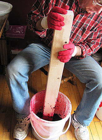Manually crushing fruit for juice extraction.