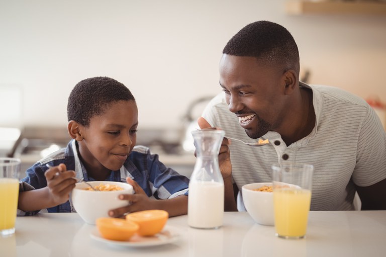 Boy and man eating breakfast cereal