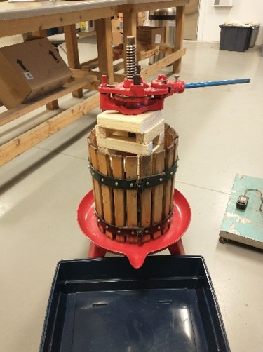 Stack of wood blocks are used as spacers in the fruit press.