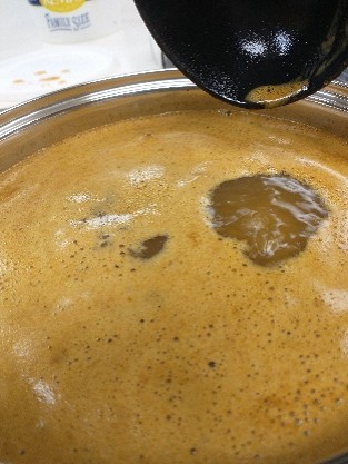 Unstrained fresh apple juice has a light-tan colored foam on top.