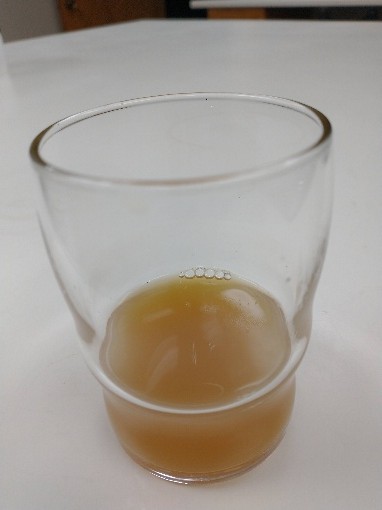 Light-tan juice in a clear glass.