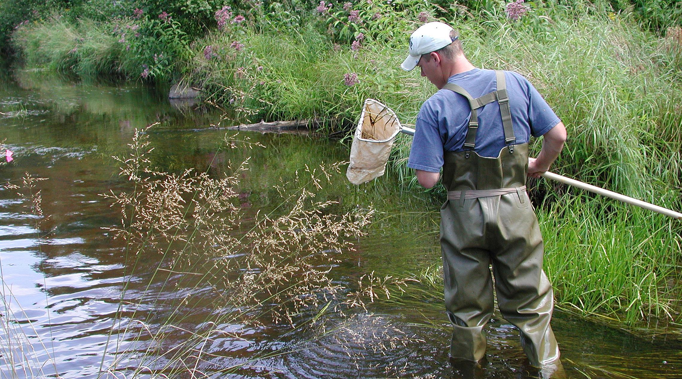 Man taking water sample from a stream