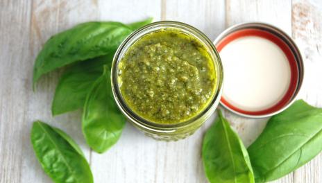 Basil Pesto, prepared and in a jar surrounded by basil leaves