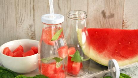 Basil and Watermelon-Infused Water, prepared in a glass bottle, with a bowl of watermelon chunks and basil leaves nearby
