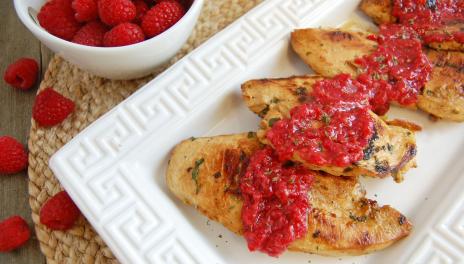 photograph of grilled chicken covered in a spicy raspberry glaze on a white serving dish