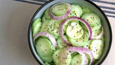 Fresh Cucumber Salad, prepared and served in a bowl, and topped with slices of red onion