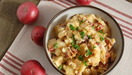 Hot Potato Salad, prepared and served in a bowl, with red potatoes nearby