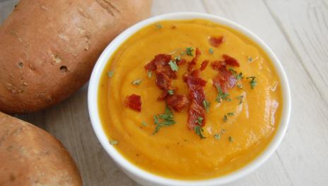 Smoked Bacon Sweet Potato Soup, served in a bowl next to several sweet potatoes