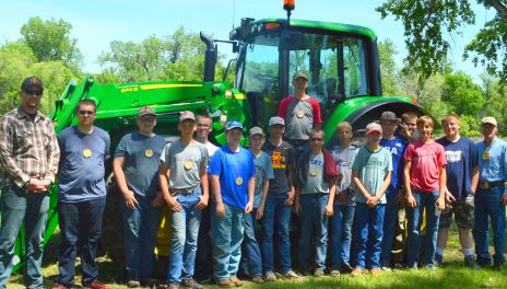 Teens posing in front of a green tractor 