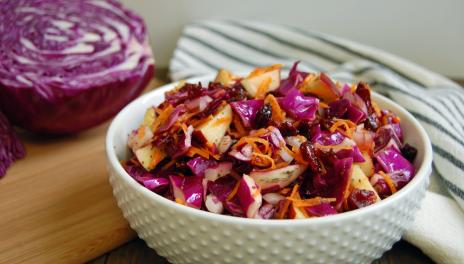 bowl of red cabbage salad with cabbage on cutting board