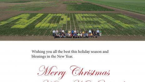 Holiday greeting with several staff members standing in a plot designed to spell NDSU in contrasting crops.