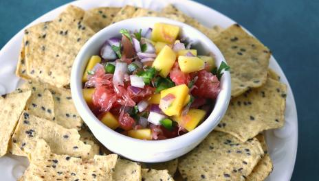 small bowl of citrus salsa with multigrain crackers