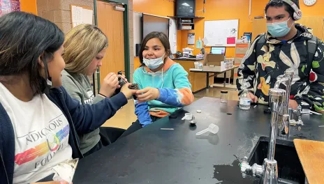 Teenage youth examine a filled jar. 