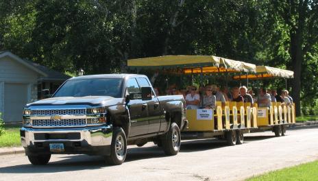 A pickup pulls two covered wagons filled with tour guests.