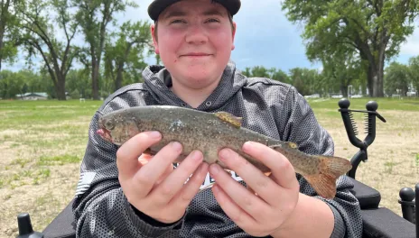 Young man holds up a fish.