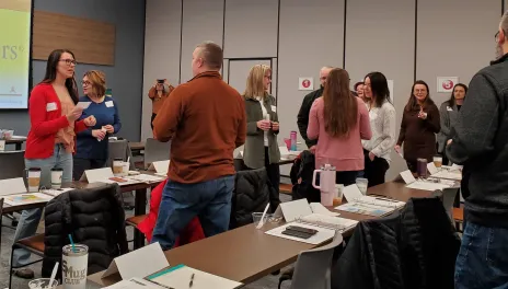 Men and women standing and talking at meeting.