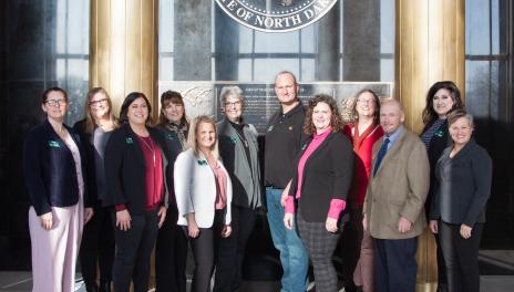 Group of people standing together under State of North Dakota seal. 