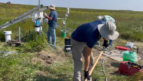 researchers in a field using equipment 