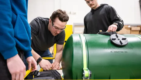 Engineering students with goggles working on a tank
