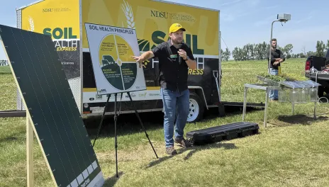 A man does a presentation on Soil Health principles in a farm field