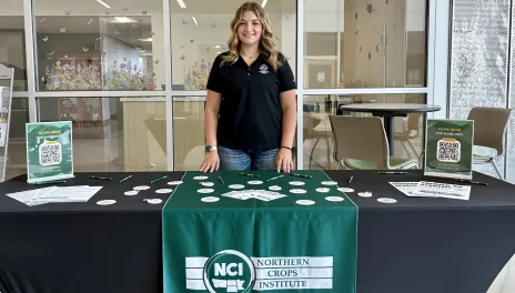 Grace Olin from NCI standing behind tradeshow booth