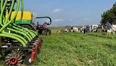 People in an alfalfa field, watching a liquid manure spreader demonstration.