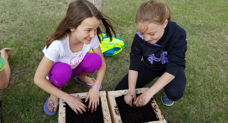 2 girls planting garden boxes