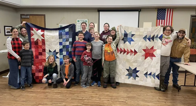 kids and volunteers displaying two quilt tops