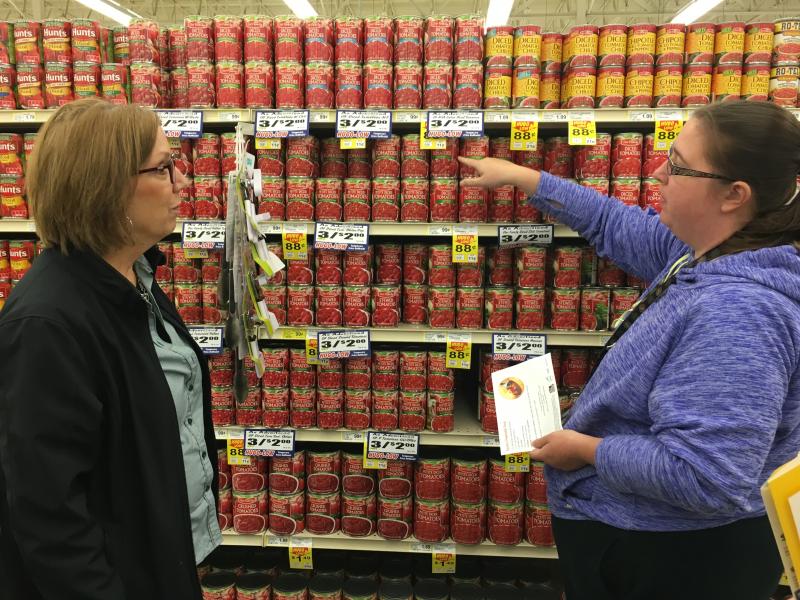 two women looking at canned tomato products