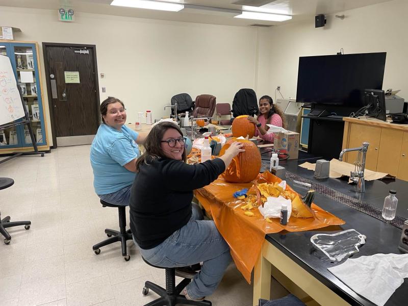 Photo of graduate students carving pumpkins for the annual pumpkin carving contest (2022)