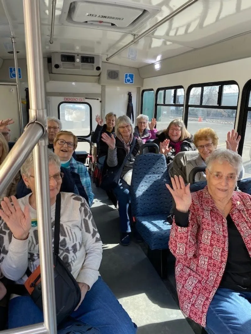 senior citizen women waving "hi" on a bus