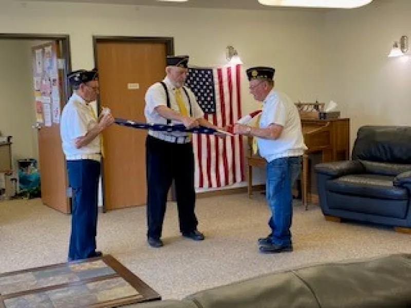 Three uniformed veterans folding the American flag