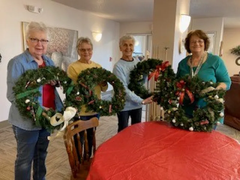Senior citizens showing off Christmas wreaths they made
