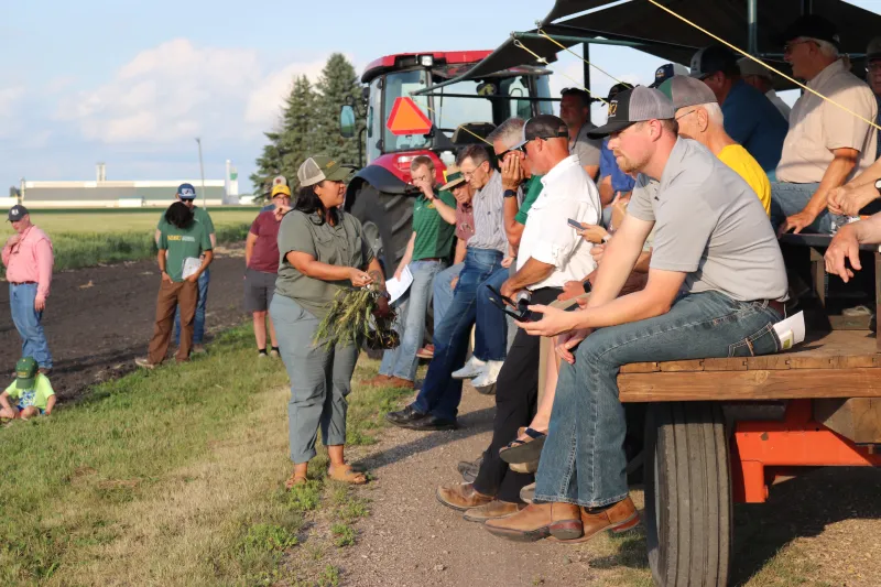 a woman talking to a group on an ag trailer