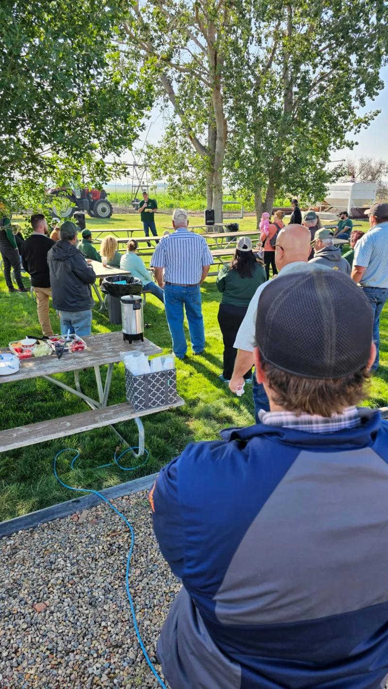 people sitting at picnic tables listening to a speaker
