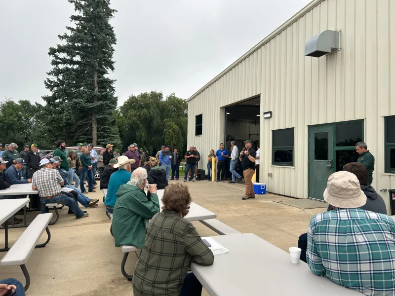 people sitting at picnic table listening to a speaker