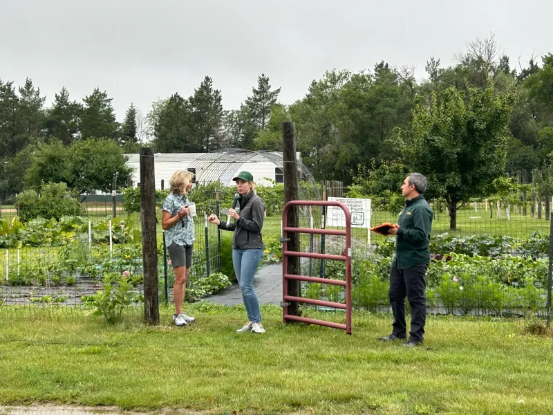 a woman gives a gardening demo in front of a garden