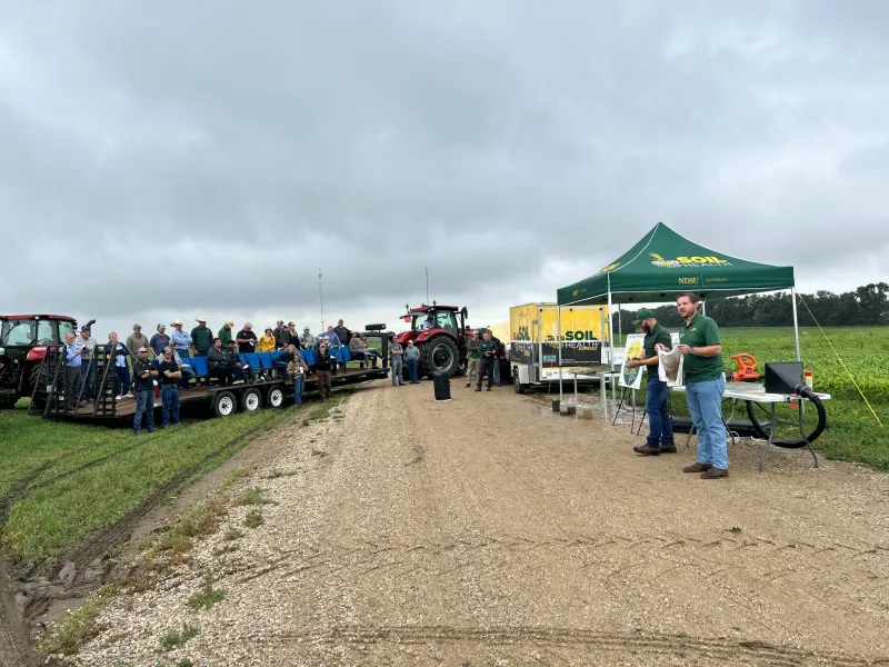 a man gives a soil health talk to a small crowd outdoors