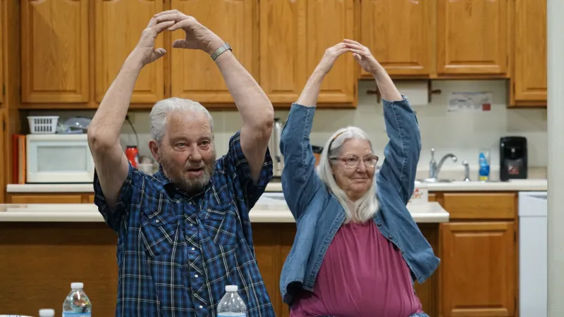 two older people doing arm stretches