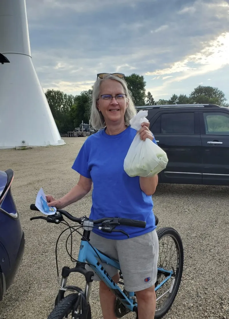 woman on bicycle holds bag of fresh vegetables