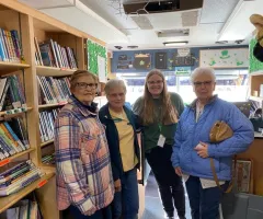 Senior citizens inside a bookmobile with shelves of books