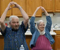 A man and a woman with arms above heads and fingers touching