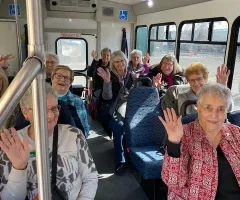 senior citizen women waving "hi" on a bus