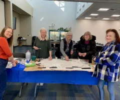 Women gluing mosaic pieces on a sign for the library 
